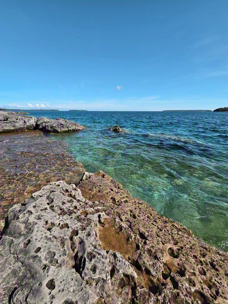 Clear green and blue water over pitted limestone ledges at the mouth of Big Tub Harbour