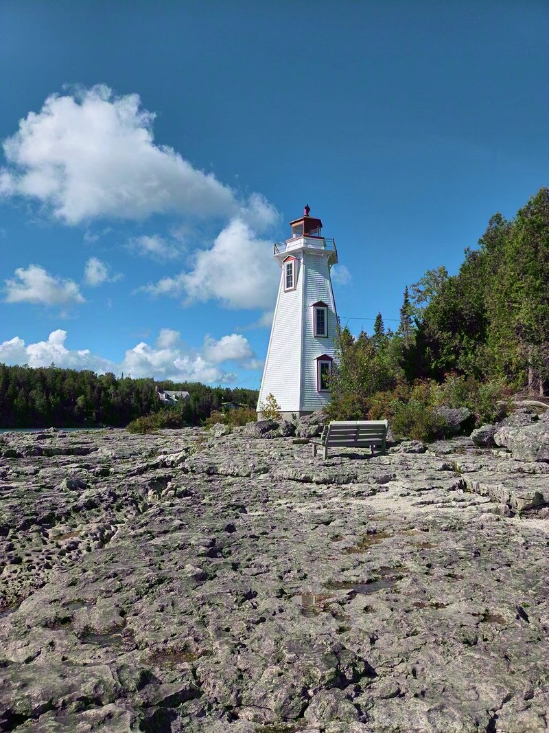 Big Tub Lighthouse standing on the flat limestone pavement above the harbour under a blue summer sky