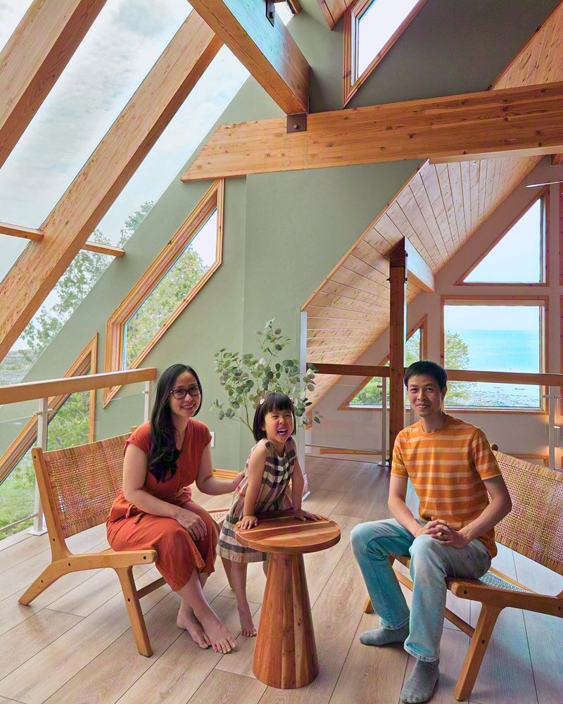 Hoan, Jenny and Emmy sitting together around a small round table in the atrium loft, lake windows behind them