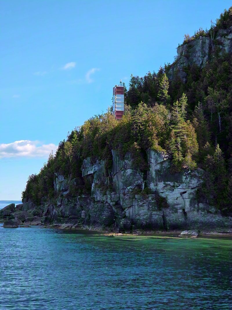 The red and white Castle Bluff light tower standing above the limestone cliff on Flowerpot Island