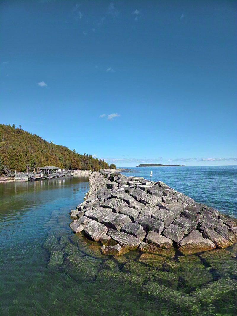 A breakwater of large stacked limestone blocks beside clear shallow water at the Flowerpot Island dock