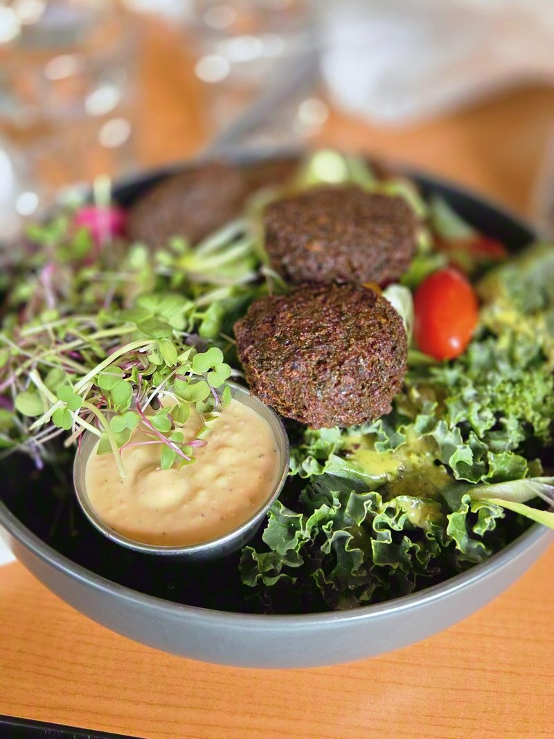 A falafel bowl with kale, greens, tomato, microgreens and a tahini dressing at the Green Door Café