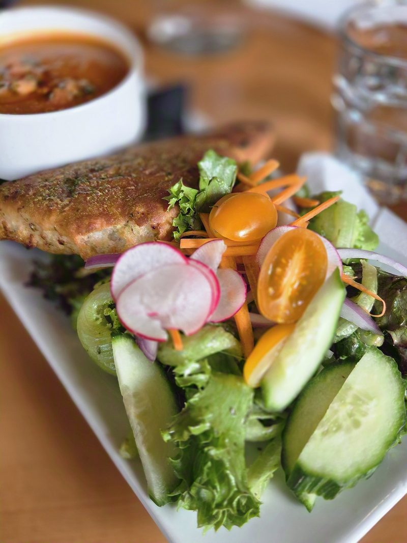 A golden savory pastry with a fresh side salad of cucumber, yellow tomato, radish and carrot