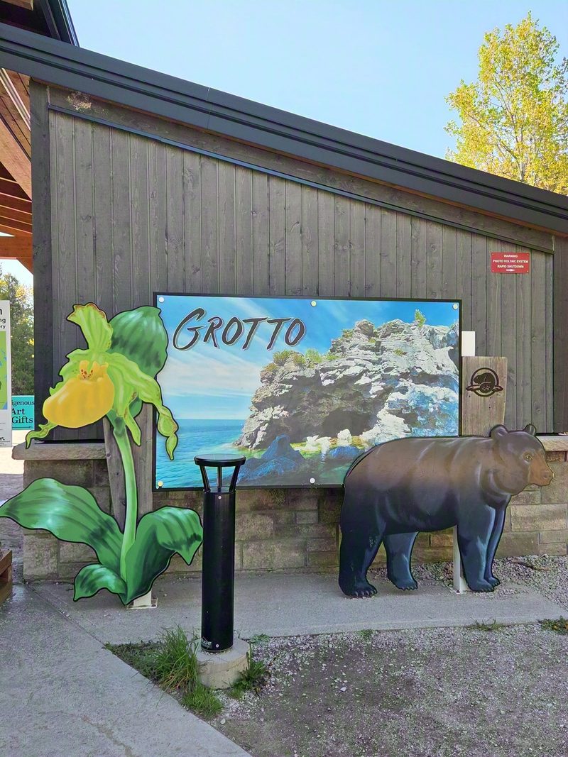 The Grotto trailhead kiosk with an illustrated interpretive board, a painted lady's slipper orchid and a black bear cutout