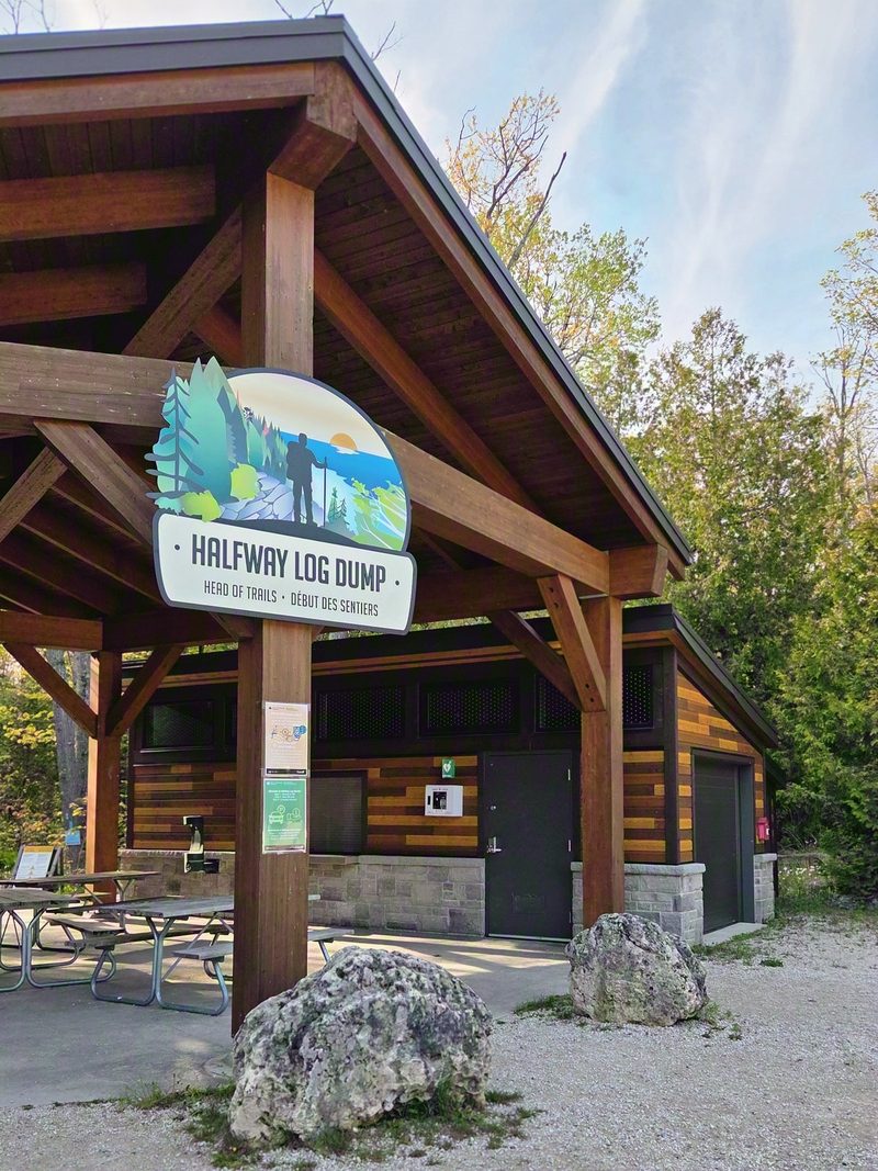 The timber trailhead pavilion at Halfway Log Dump with its head-of-trails sign, washrooms and picnic tables