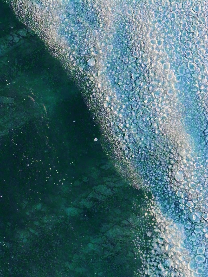The edge of the ice sheet meeting open turquoise water over limestone, seen from above