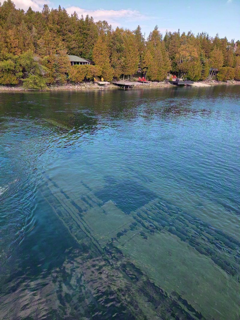 The hull of the schooner Sweepstakes lying on the bottom of Big Tub Harbour, clearly visible through clear green water