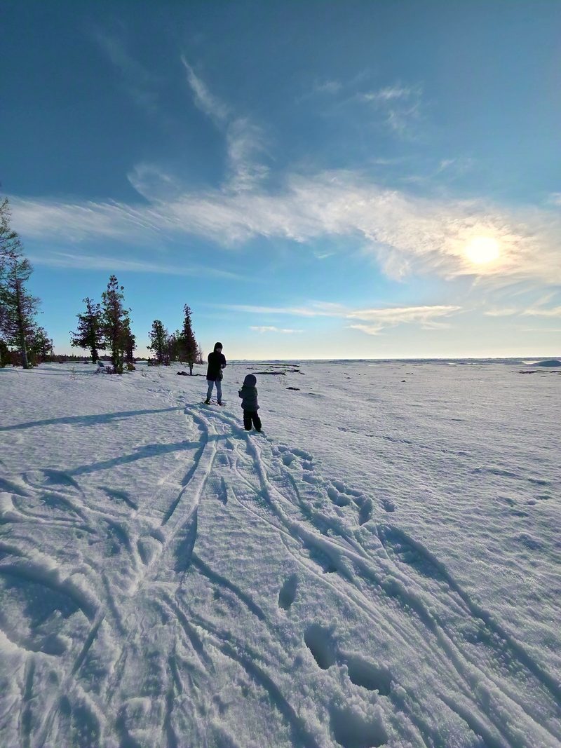 2 people far out on open snow in low evening sun, their shadows running long across the drifts
