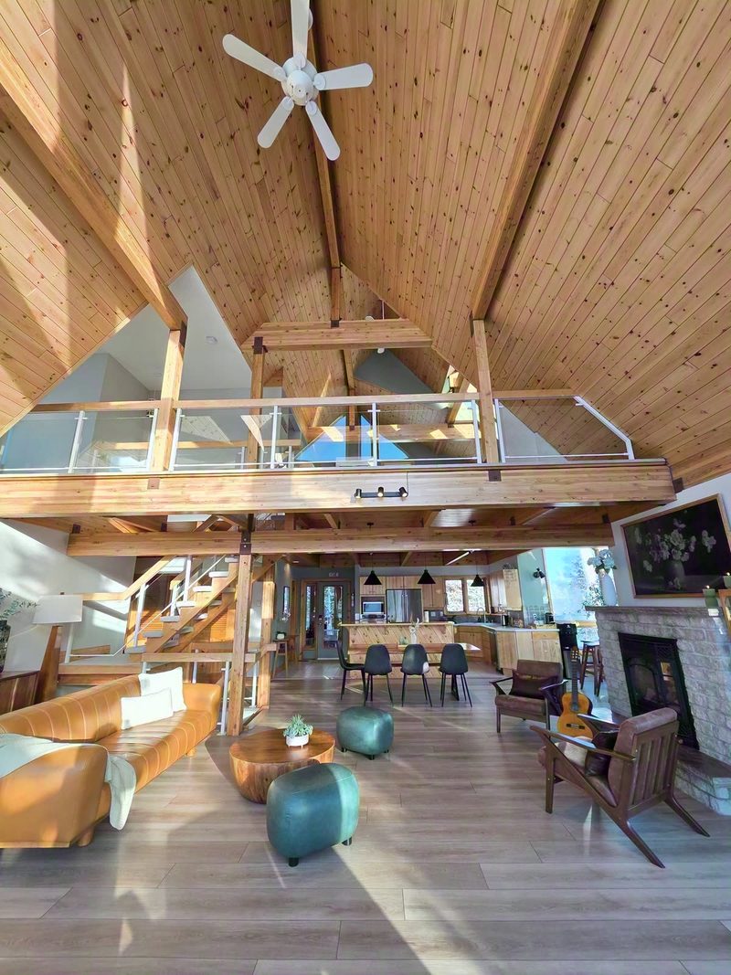 Looking up through the atrium past the fireplace to the loft bridge and pine ceilings