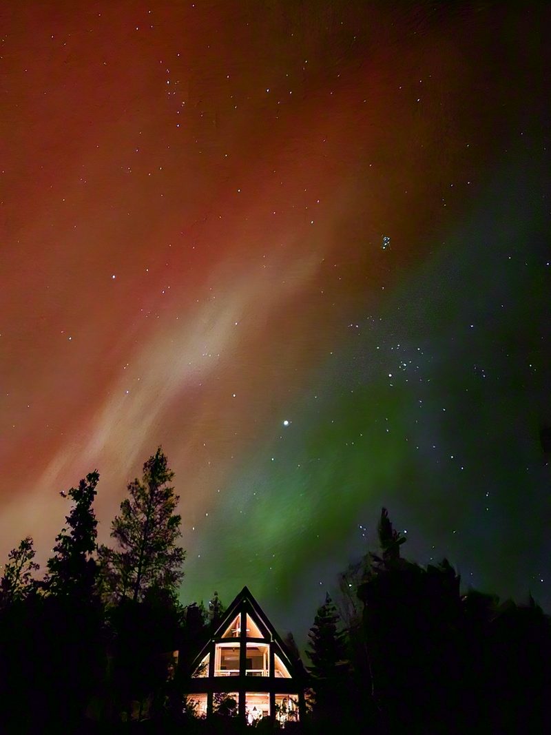 Red and green northern lights over the cottage at night