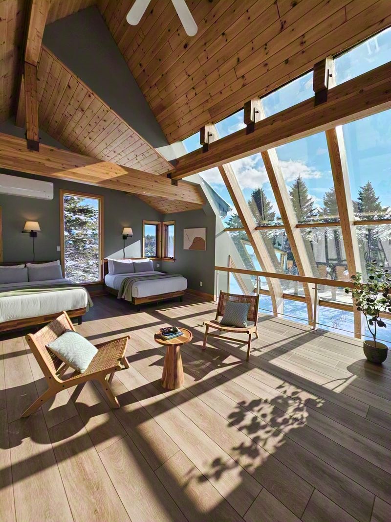 Cielo loft with bed, wooden chairs and sun streaming through the angled glass onto the floor