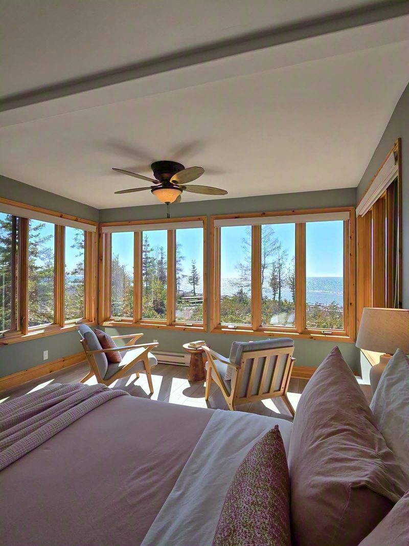 Delfina's king bed and window-wrapped sitting corner in soft spring light