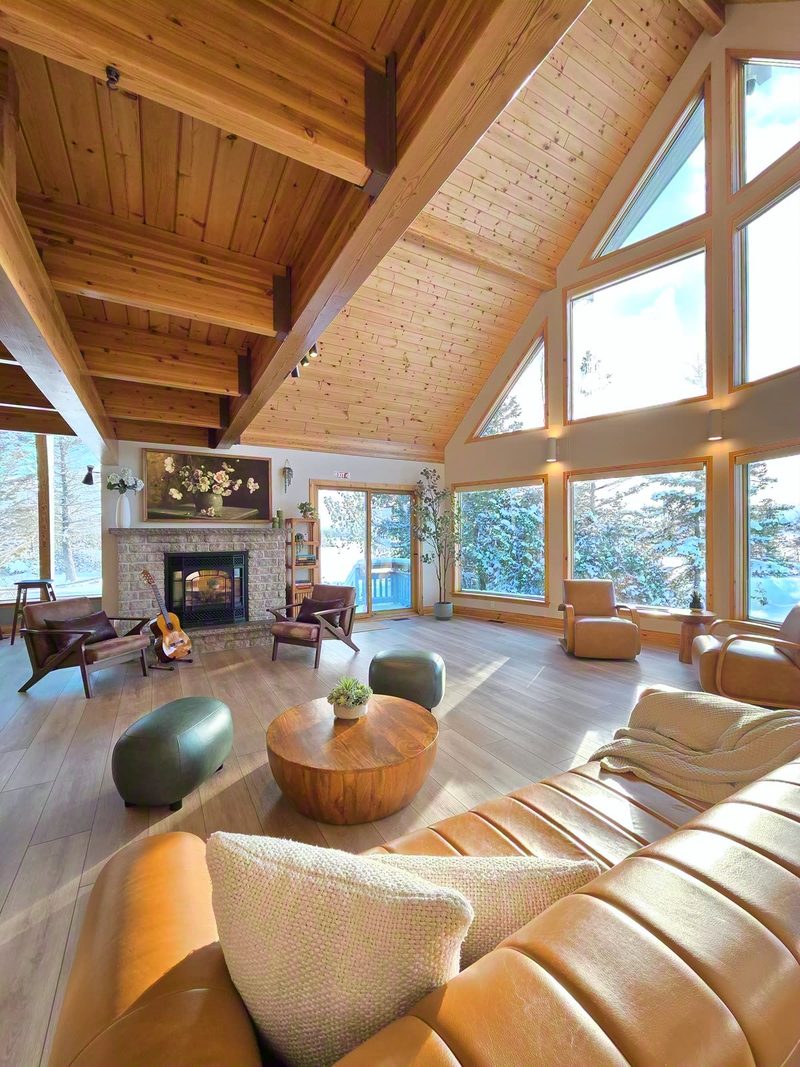 The great room seen from behind the leather sofa: fireplace, poufs and cathedral windows in winter light