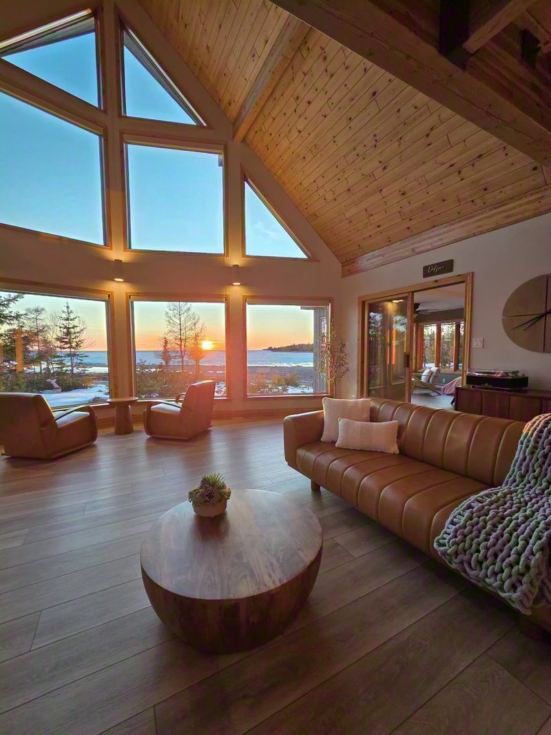 The low sun bursting through the great room prow windows over the leather sofa