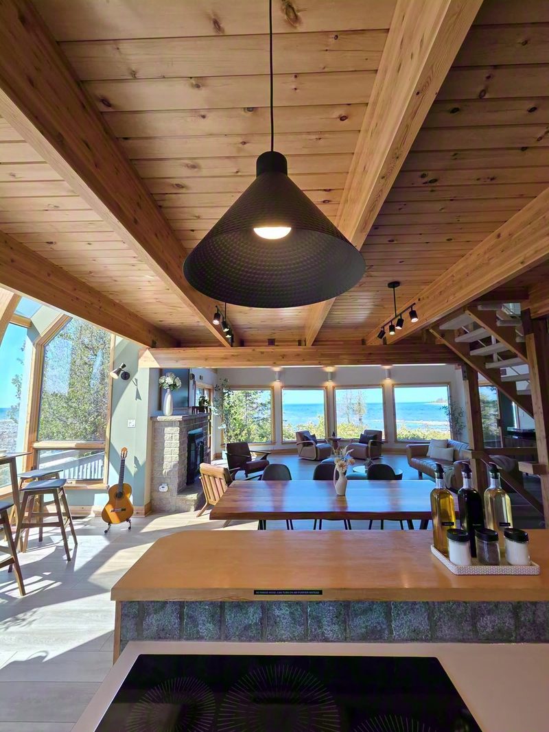 Kitchen island with pendant light looking down the timber-framed great room to the lake windows