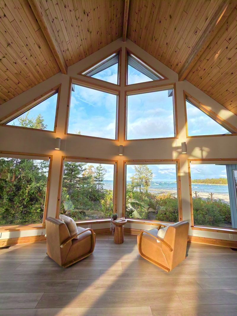 Golden morning light filling the sunroom's wrap-around windows over two armchairs