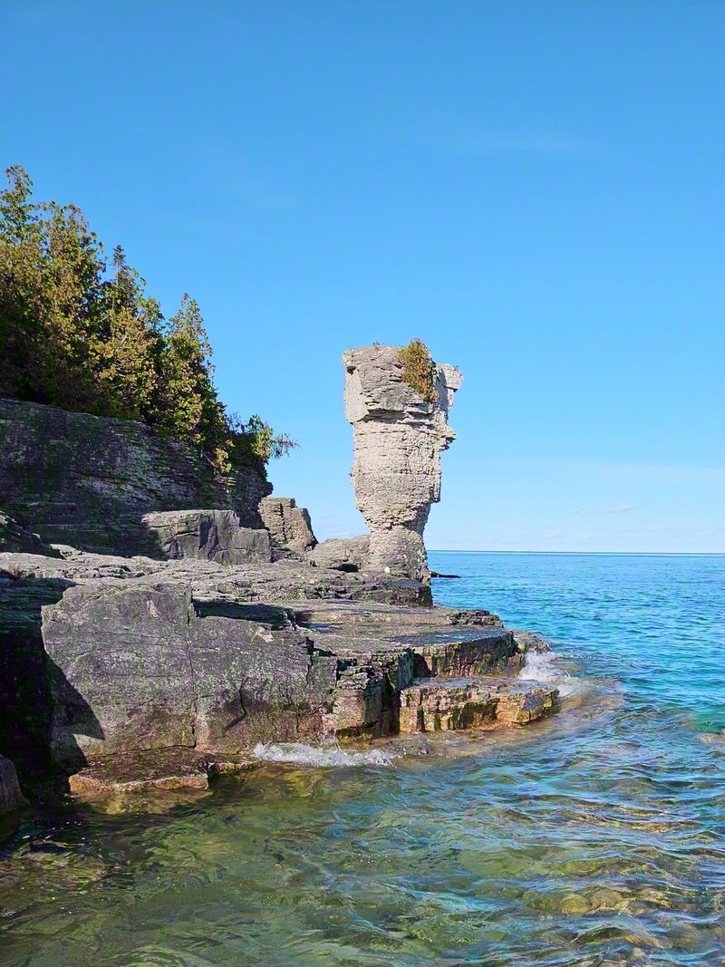 The tall flowerpot rock formation on Flowerpot Island beside clear turquoise Georgian Bay water