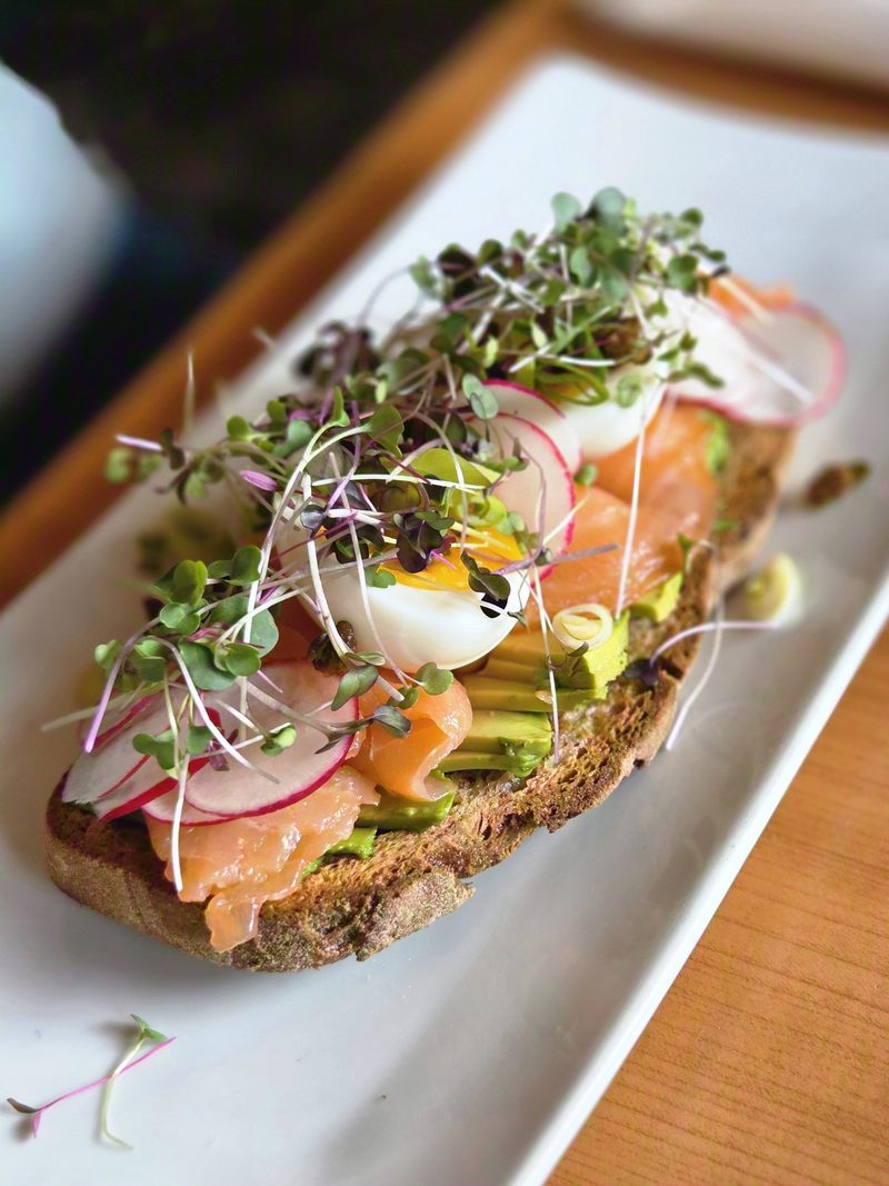 Open-faced smoked salmon toast with avocado, soft egg and microgreens at Green Door Café