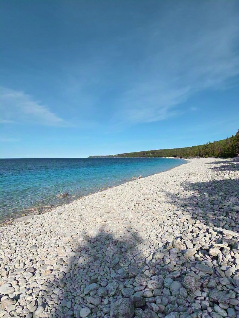 The long white cobble beach at Halfway Log Dump curving away beside deep blue water